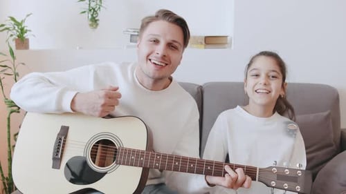 Father and Daughter Sing and Play Acoustic Guitar