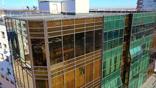 Flying around the top of the building with mirror windows. Sight of the road in the city centre.