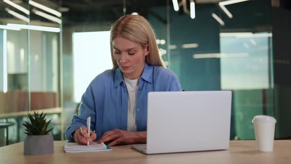 Focused Lady Making Remarks in Notebook While Sitting By Desktop and ...