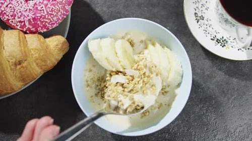 Stirring banana and granola breakfast bowl