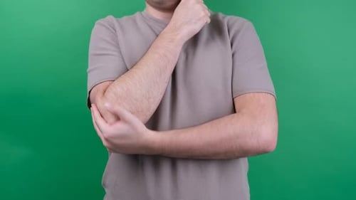Adult Massaging Elbow on Green Background