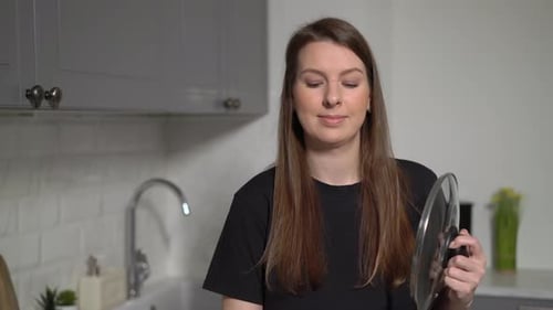 Woman Samples Food in Modern Kitchen with a Smile
