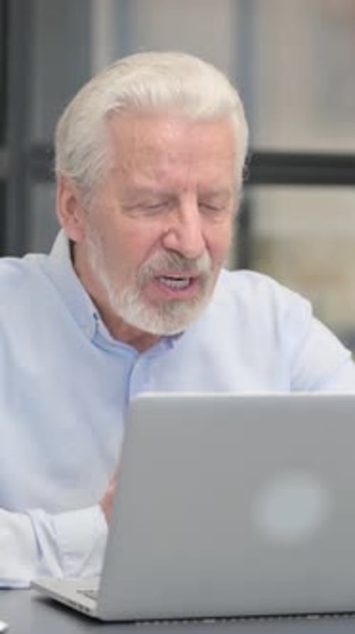 Old Businessman Chatting Online on Laptop while Sitting in Office, vertical video
