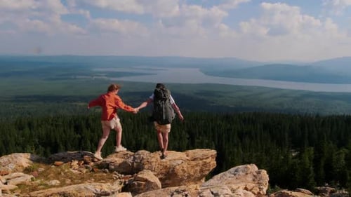 Young Woman and Man Walking Down the Mountain and Looking at the Forest