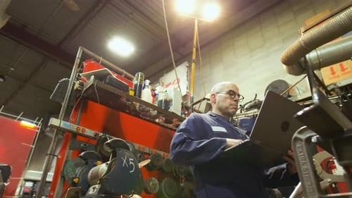 Männlicher Schweißer mit Laptop arbeitet in einer Industriewerkstatt 50-54 Jahre
