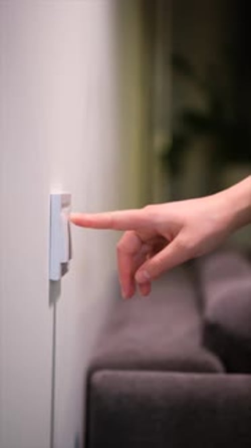 Hand Turns Light Switch on and Off in Room