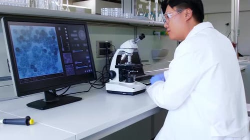 Scientist Examines Sample With Microscope in Lab