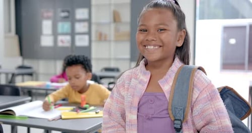 In school, smiling girl with backpack standing in classroom, students studying