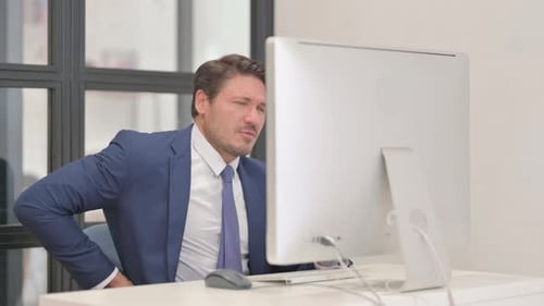 Empresário de meia idade com lesão na coluna vertebral trabalhando no desktop