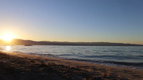 Two man running into the mediterranean sea with sunrise in the background