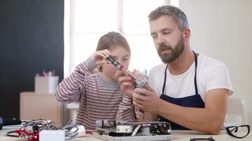Small Girl with Man at Repair Cafe Repairing Household Electrical Devices