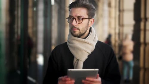 Business Man Walks in City Street and Using Digital Tablet