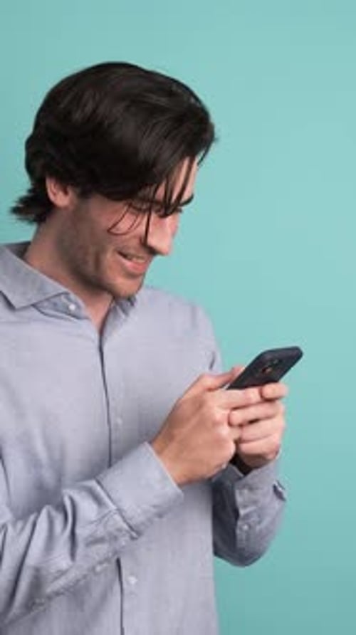 Happy Adult Man Using Smartphone in Blue Studio