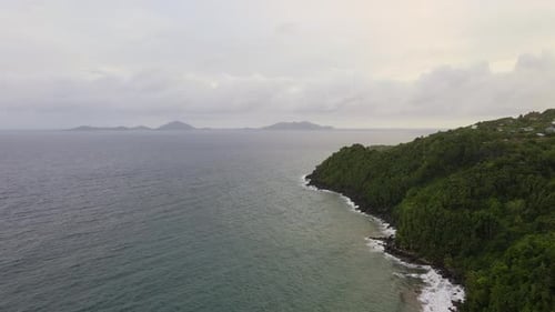 Immenses Meer neben der Insel mit Bäumen, Wolken im Hintergrund an einem bewölkten Tag. Drohnenschuss aus der Luft.