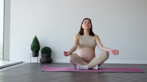 Pregnant Woman Meditating in Lotus Position on Yoga Mat