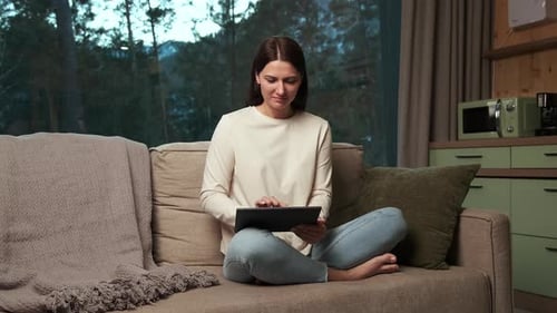Woman Using Tablet on Couch Indoors