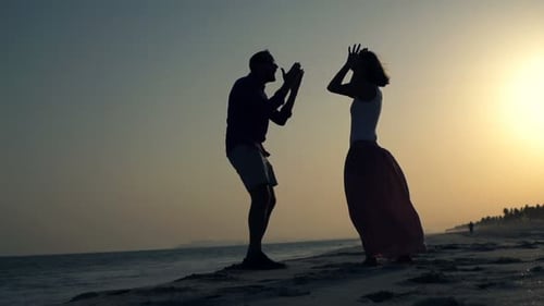Silhouette eines Paares, das sich in den Ferien bei Sonnenuntergang heftig am Strand streitet