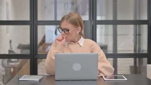 Coughing Young Woman Using Laptop in Office