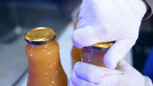 Les mains dans des gants d'un ouvrier d'une usine alimentaire mettent les bouchons sur les bouteilles.