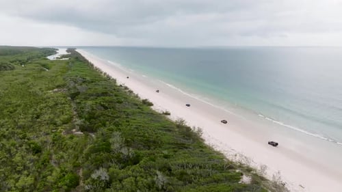 Aerial view of sandy beach and jeep by ocean, Australia.