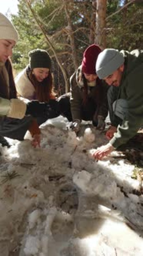 Group of Friends Investigating Snow in Winter Forest