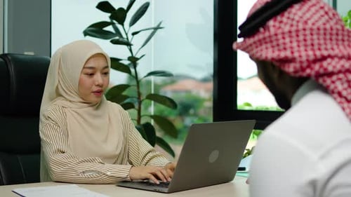 Two diverse businessmen and woman discussing financial market data using laptop and digital tablet.