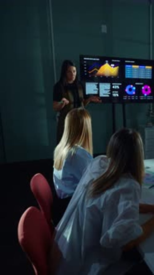 Business Analyst Presenting Data Visualization Charts to Colleagues in a Modern Office Meeting