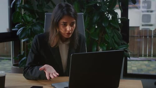 Young Woman is Making a Video Call in the Office A Female Conducts a Virtual Meeting on a Laptop