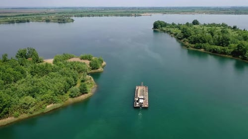 Fllowing the industrial boat filled with sand sailing in the water. Sun reflection. Hungary