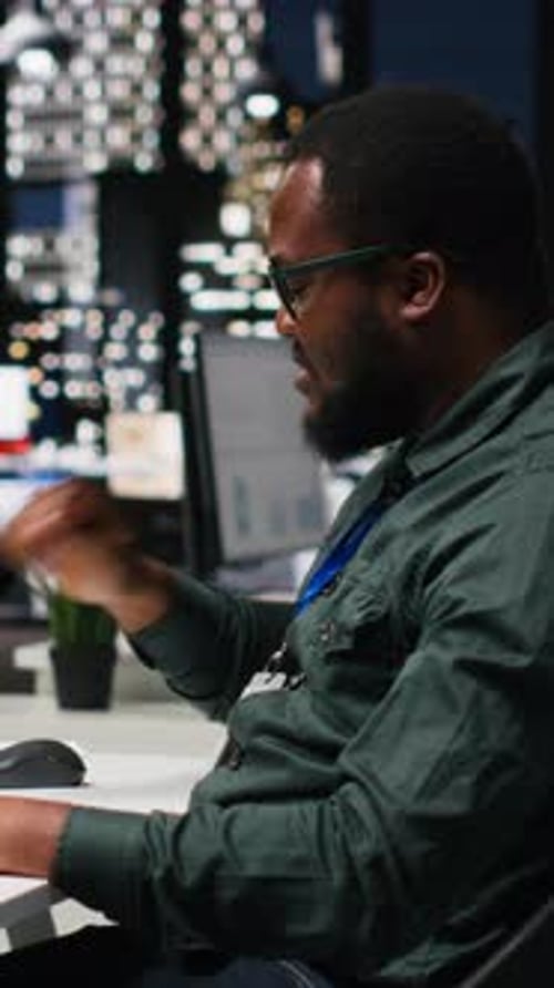 Vertical Video Office Worker Reviewing KPI Metrics on Monitor and Analytics on Desktop