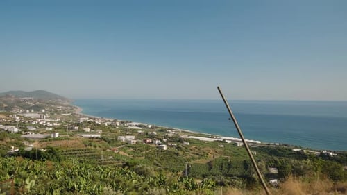 Ascending a Hill in Slow Motion, a Car Window View Reveals Verdant Countryside and Sparkling Sea