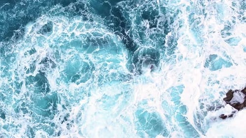 Waves crashing on rocky shore with stunning turquoise ocean water