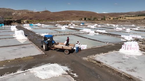 Aerial View Of Workers Working In Salt Ponds