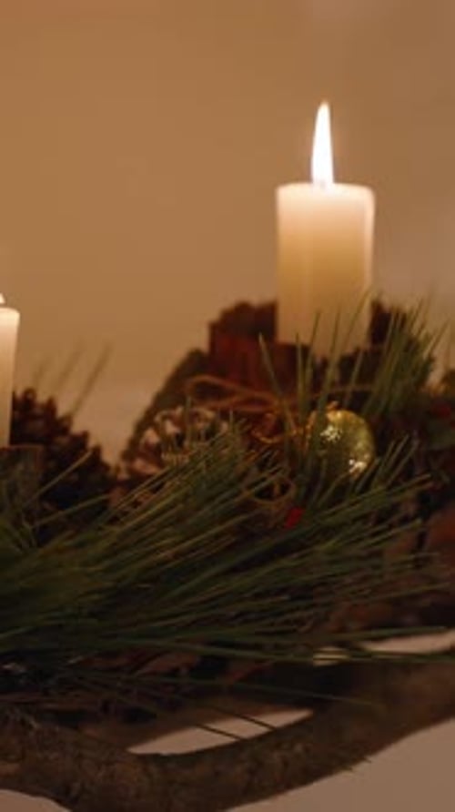 Vertical video. On the wall, there's a handmade installation with Christmas ornaments and candle hol