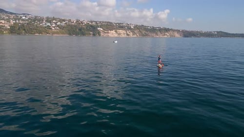 Aerial View of a Man Paddling a Standup Paddleboard or SUP Board on a Calm Sea