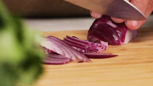Slicing Red Onion with Knife on Wooden Board