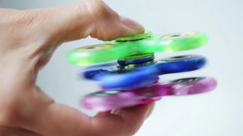 Juega a mano con tres coloridos fidget spinners, un popular invento de juguete moderno