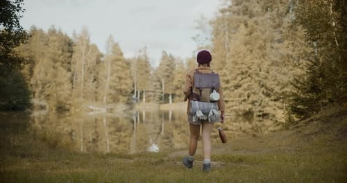 Exploradora feminina com mochila explorando à beira do lago