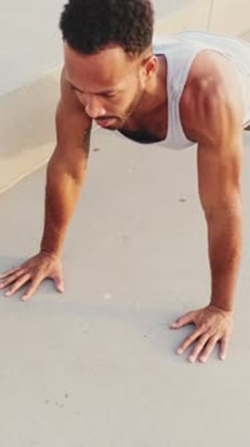 Young athlete doing workout, push ups on the embankment