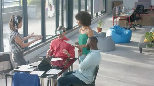 Caucasian businessman wearing vr headset while colleagues watching him at office