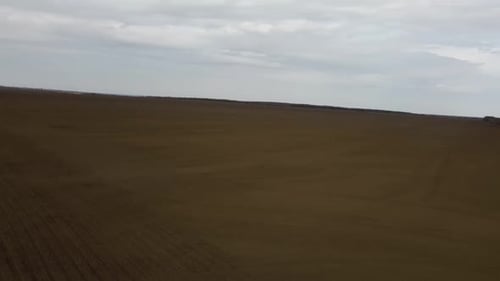Blue tractor with yellow seeder working on the field in Ukraine OA