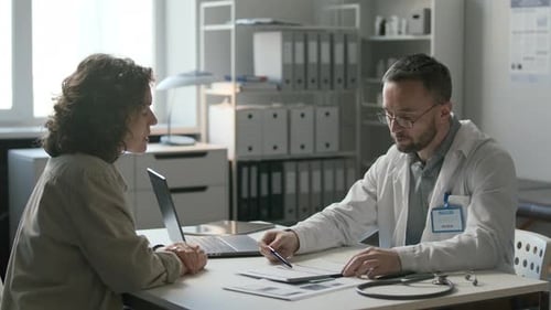 Doctor Discussing Medical Records with Female Patient in Clinic