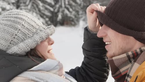Laughing Young Couple in Snow-Covered Winter Forest