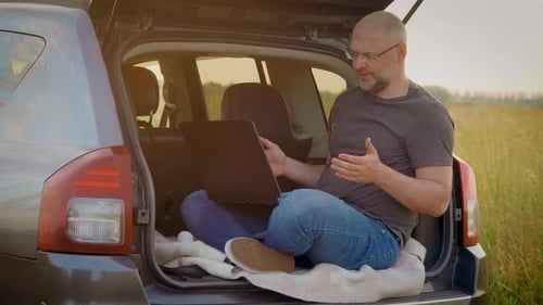 Homem adulto se comunicando por videochamada falando olhando para um laptop à distância da conferência on-line