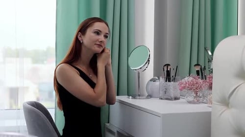 Woman Putting on Earring at Vanity Mirror