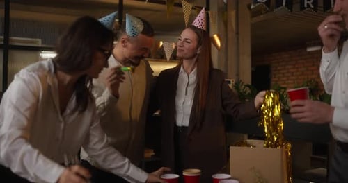 Happy Girl in Party Caps se comunica com seus colegas em roupas de negócios enquanto se prepara para uma