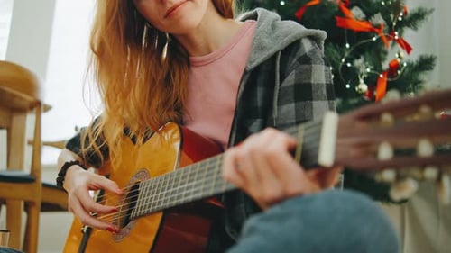 Woman Plays Guitar at Christmas Indoors