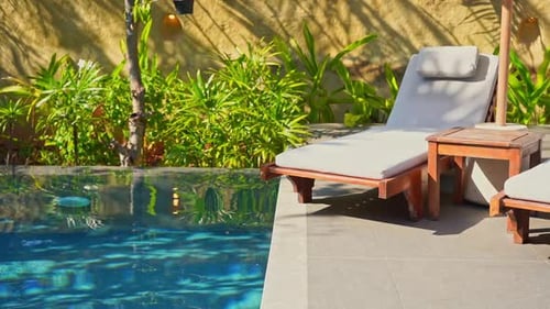 Entspannungsbereich im Freien am Pool und Grünpflanzen im Hintergrund. Statischer Schuss