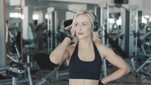 Slow motion workout with focused girl wearing headphones at a modern gym