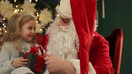 Little Girl Receiving Gift from Santa at Christmas